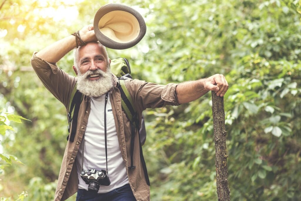 A senior hiker with a camera on a wooded trail