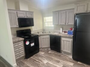Kitchen with gray cabinets, black appliances and wood-look flooring